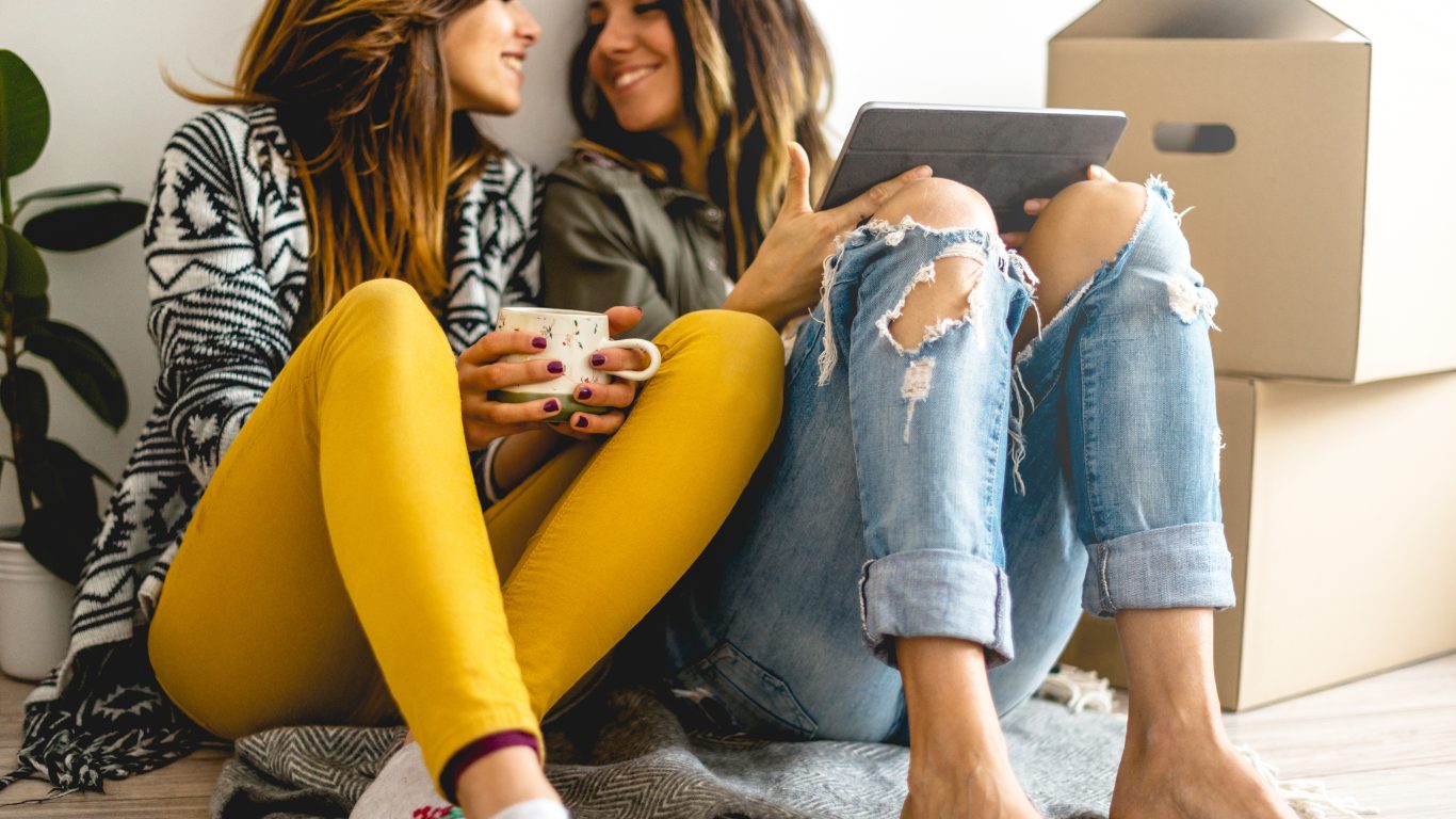 2 women sitting on the floor drinking coffee